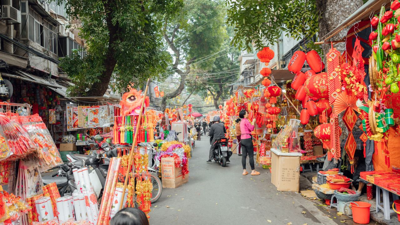 Hanoi street market lined with red lanterns and festive decorations for Lunar New Year celebrations.