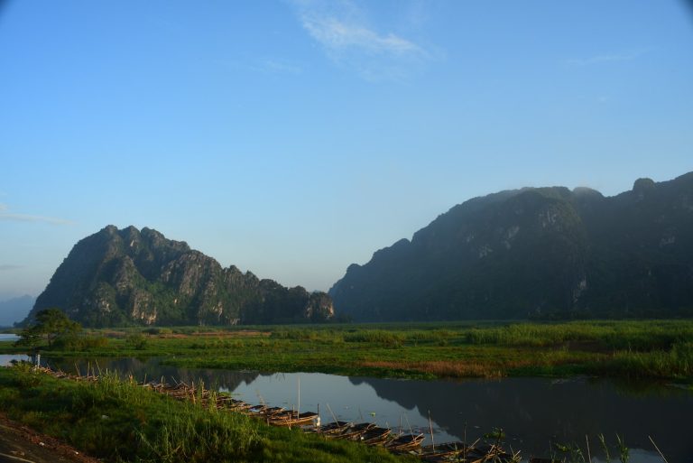 Mountains rising over a calm river at dawn in Laos