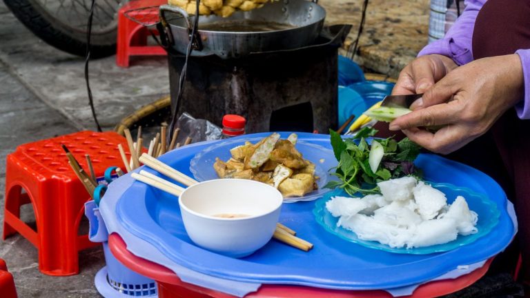A vendor prepares fresh spring rolls and noodle soup at a street food stall in Hanoi, Vietnam.