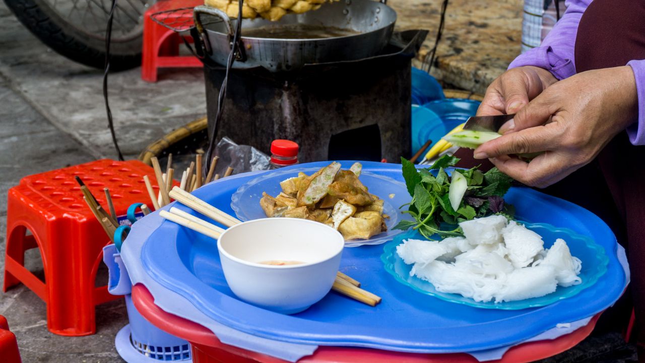 A vendor prepares fresh spring rolls and noodle soup at a street food stall in Hanoi, Vietnam.