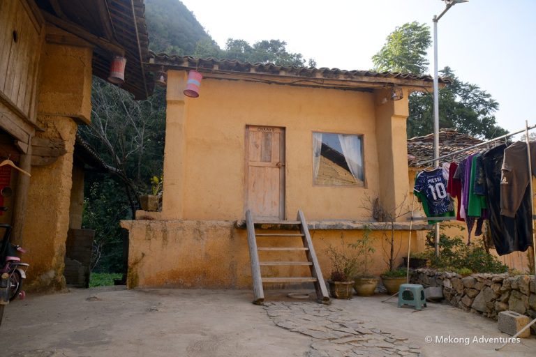 Yellow rammed-earth house with wooden steps in Then Pa village, Ha Giang