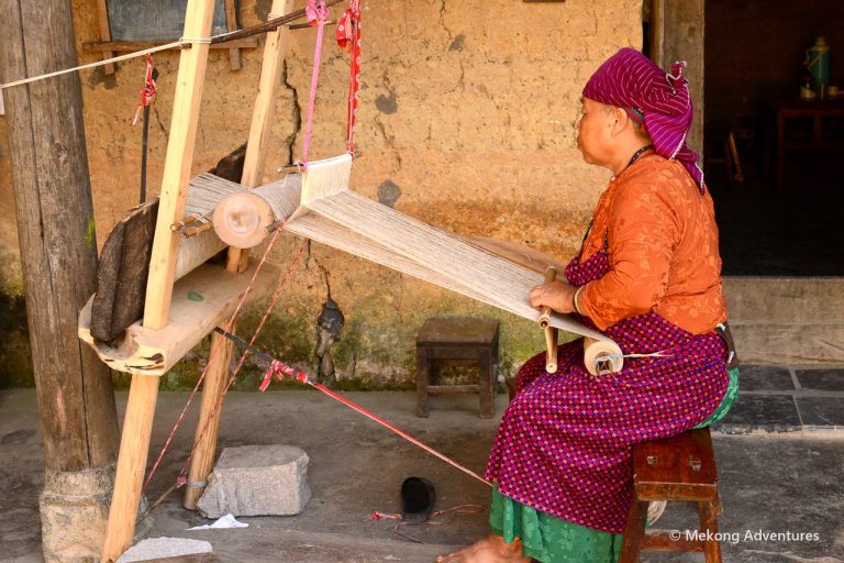 Hmong woman weaving linen on a wooden loom in Then Pa village