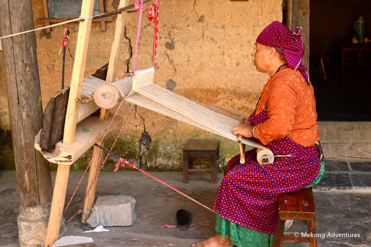 Hmong woman weaving linen on a wooden loom in Then Pa village