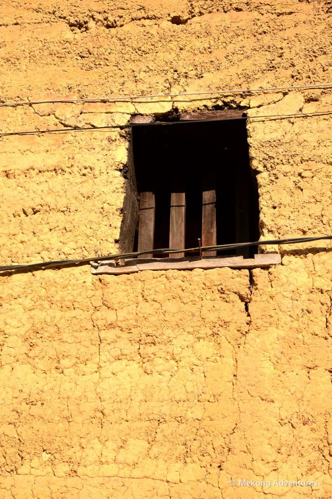 Small wooden window in a rammed-earth wall, Then Pa village
