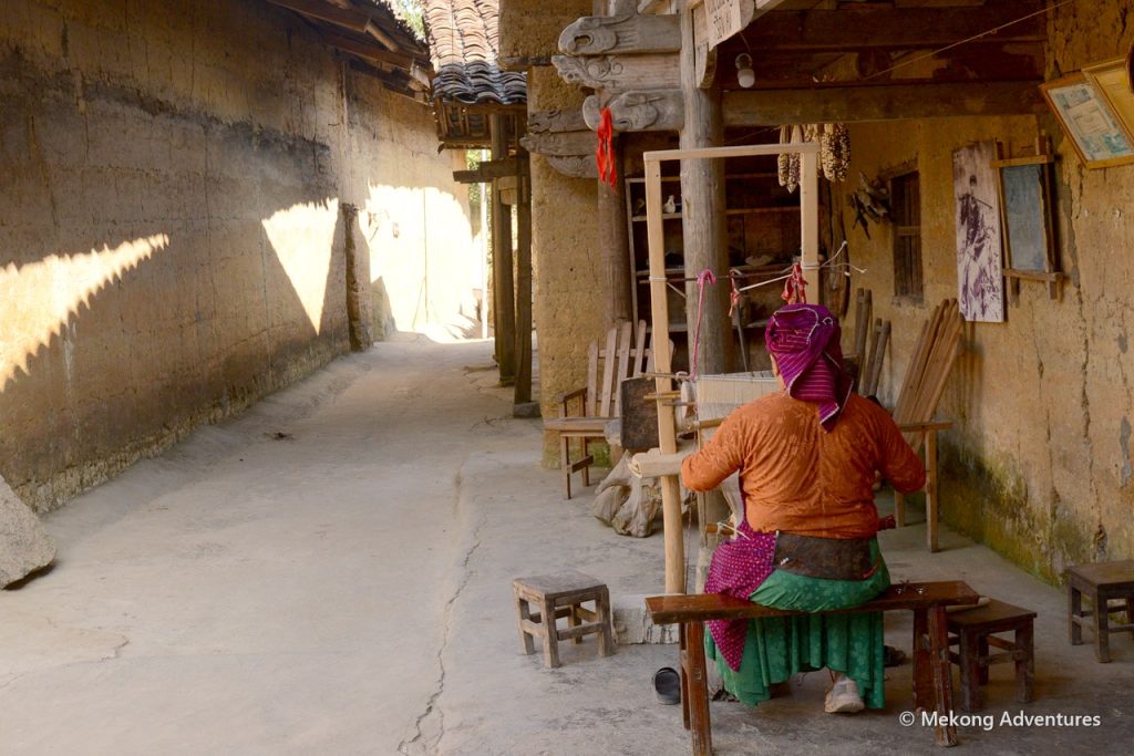 Woman working at a loom in the courtyard of a Then Pa home