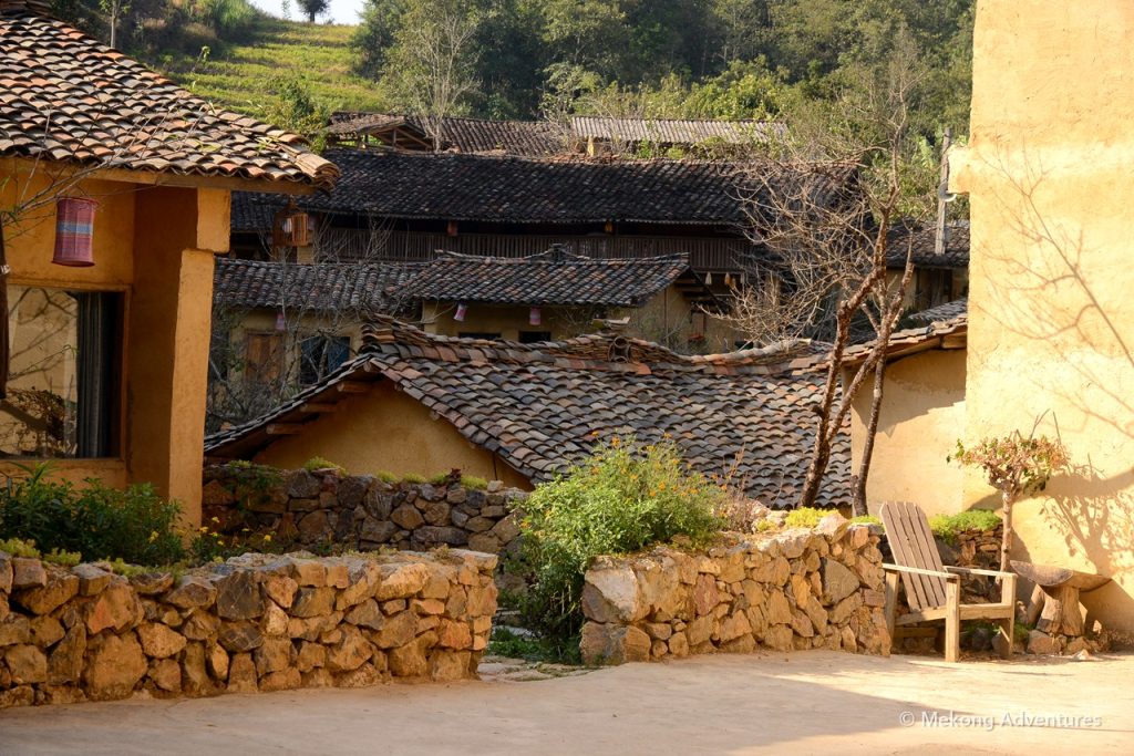 Stacked firewood and stone walls outside houses in Then Pa village