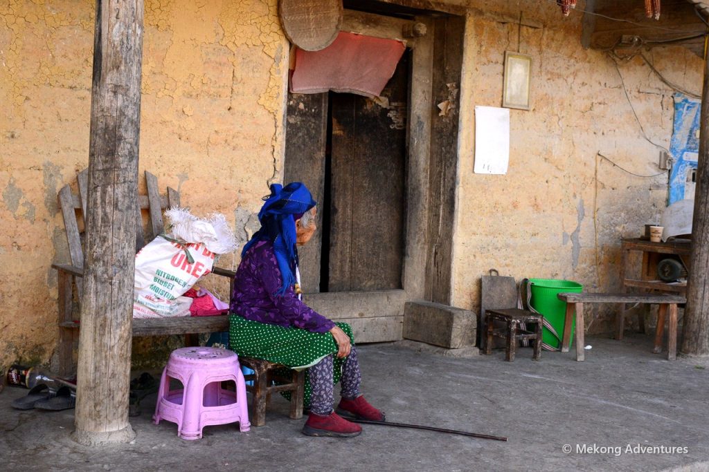 Elderly woman resting outside her home in Then Pa village