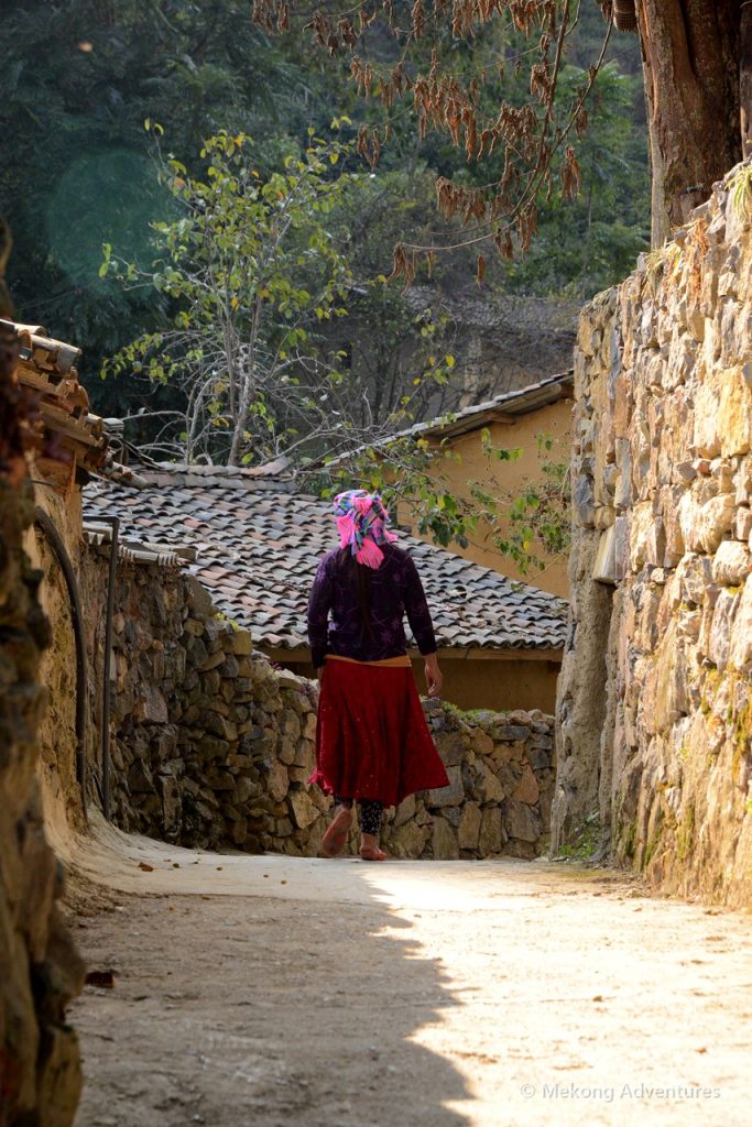 Woman in traditional dress walking a stone lane in Then Pa